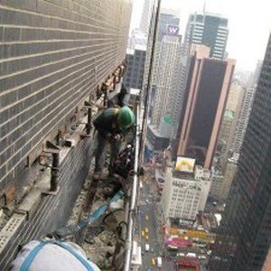 A man is working on the side of a building with a sign that says w on it