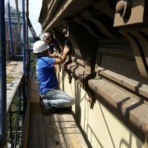 A man wearing a hard hat is working on a building