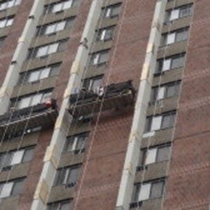 A man is working on the side of a tall building.