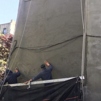 Two men are working on the side of a building.
