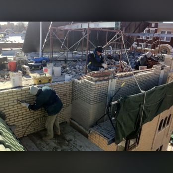 A group of construction workers are working on a brick wall