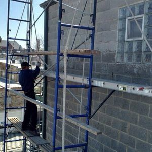 A man is standing on a scaffolding on the side of a building.