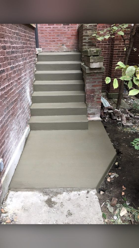 A set of concrete stairs leading up to a brick wall.