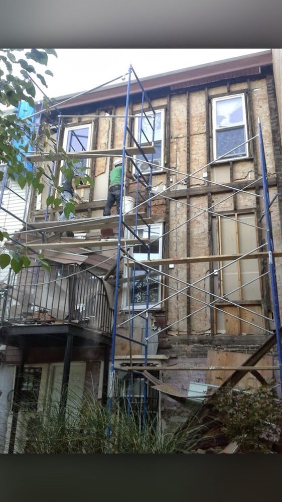 A man is standing on a scaffolding on the side of a building.