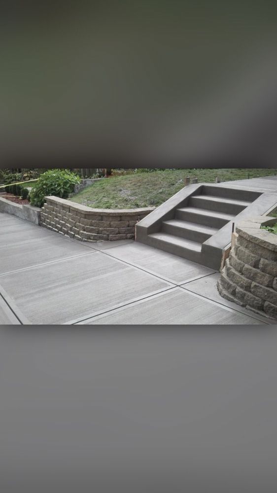A concrete walkway with stairs and a stone wall.