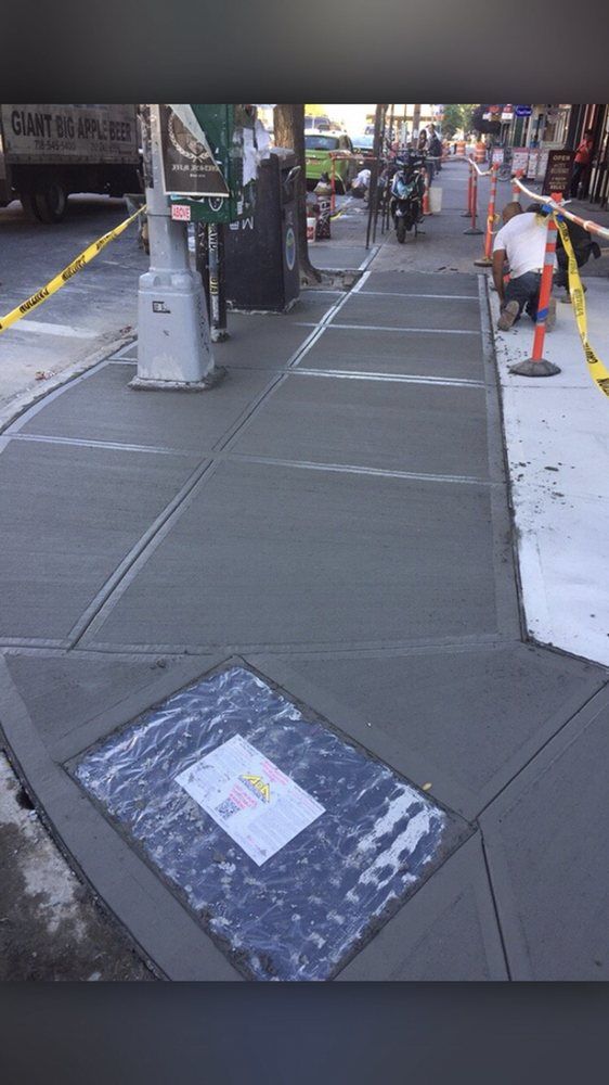 A concrete sidewalk is being repaired on a city street.