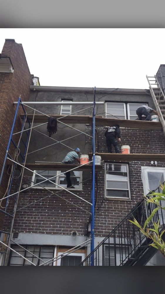 A group of men are working on a brick building with scaffolding.