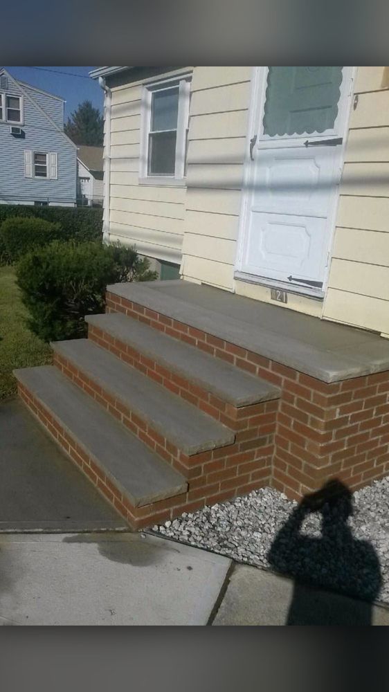 A brick porch with concrete steps and a white door
