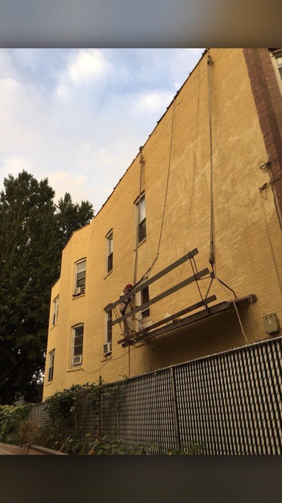 A man is standing on a scaffolding on the side of a building.