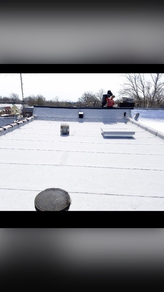 A person is standing on top of a white roof.