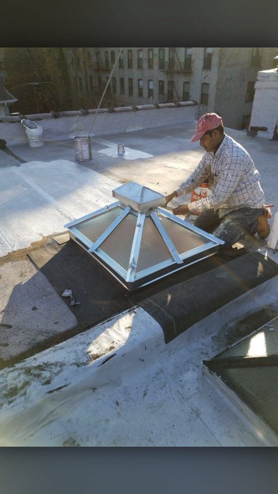 A man is working on a skylight on the roof of a building.