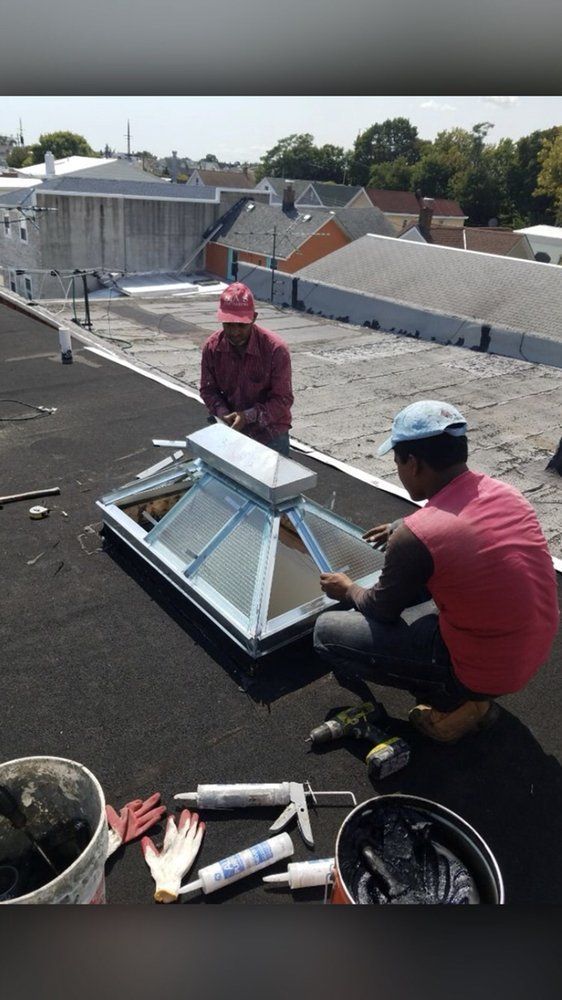 Two men are working on a skylight on a roof