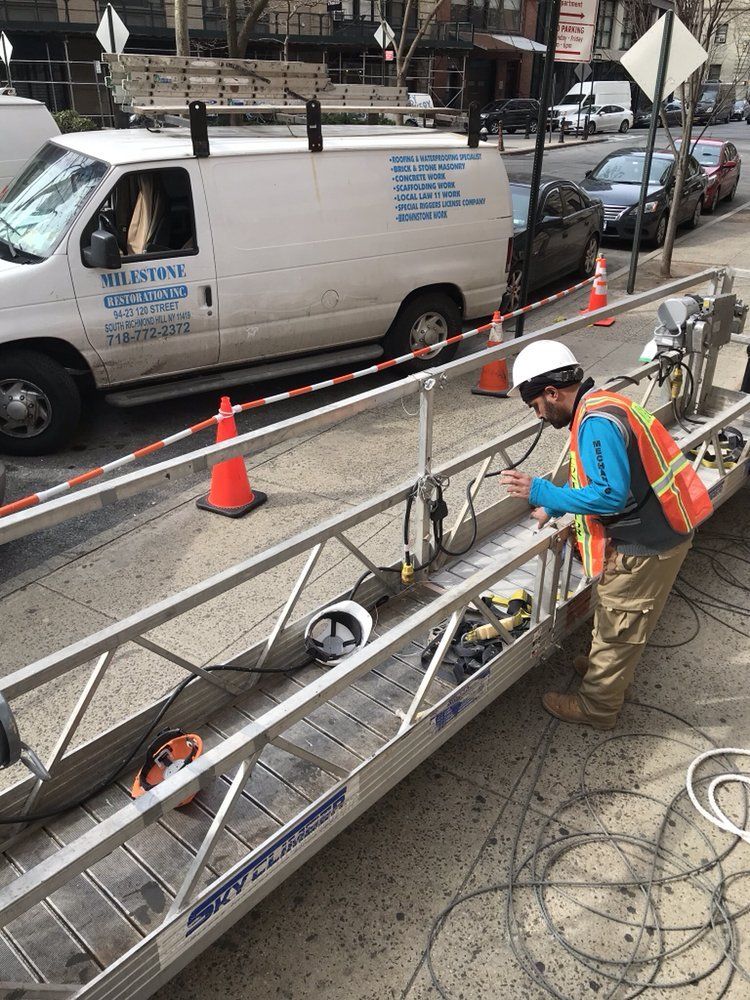 A man is working on a ladder on the side of the road.