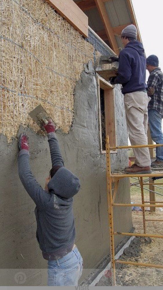 A group of people are working on a wall on a scaffolding.