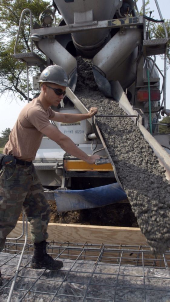A man is pouring concrete into a concrete mixer.