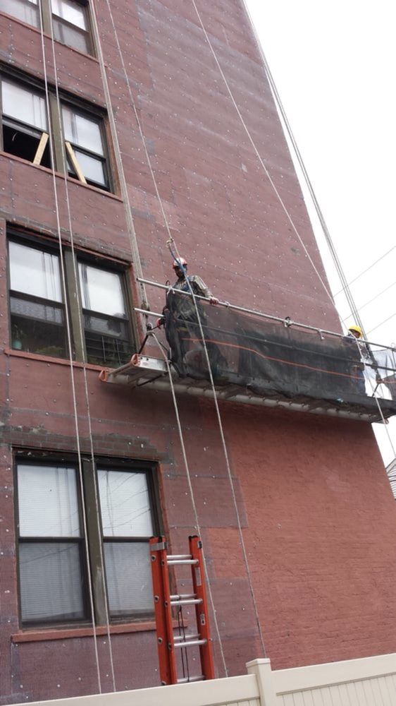 A man is working on the side of a building with a ladder.