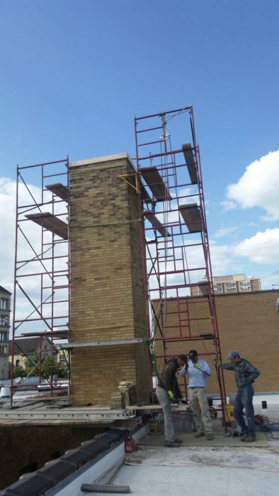 A group of construction workers are working on a brick chimney