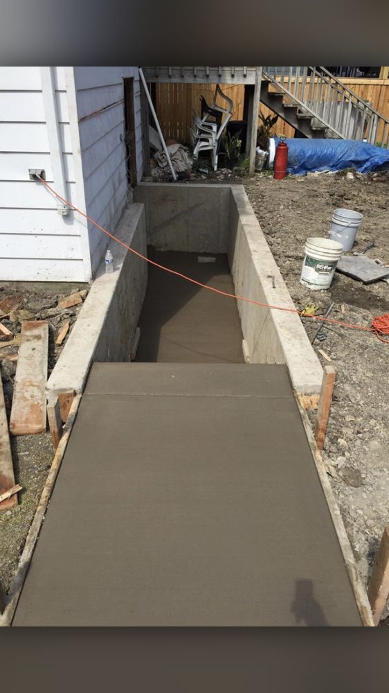 A concrete walkway is being built in front of a house.