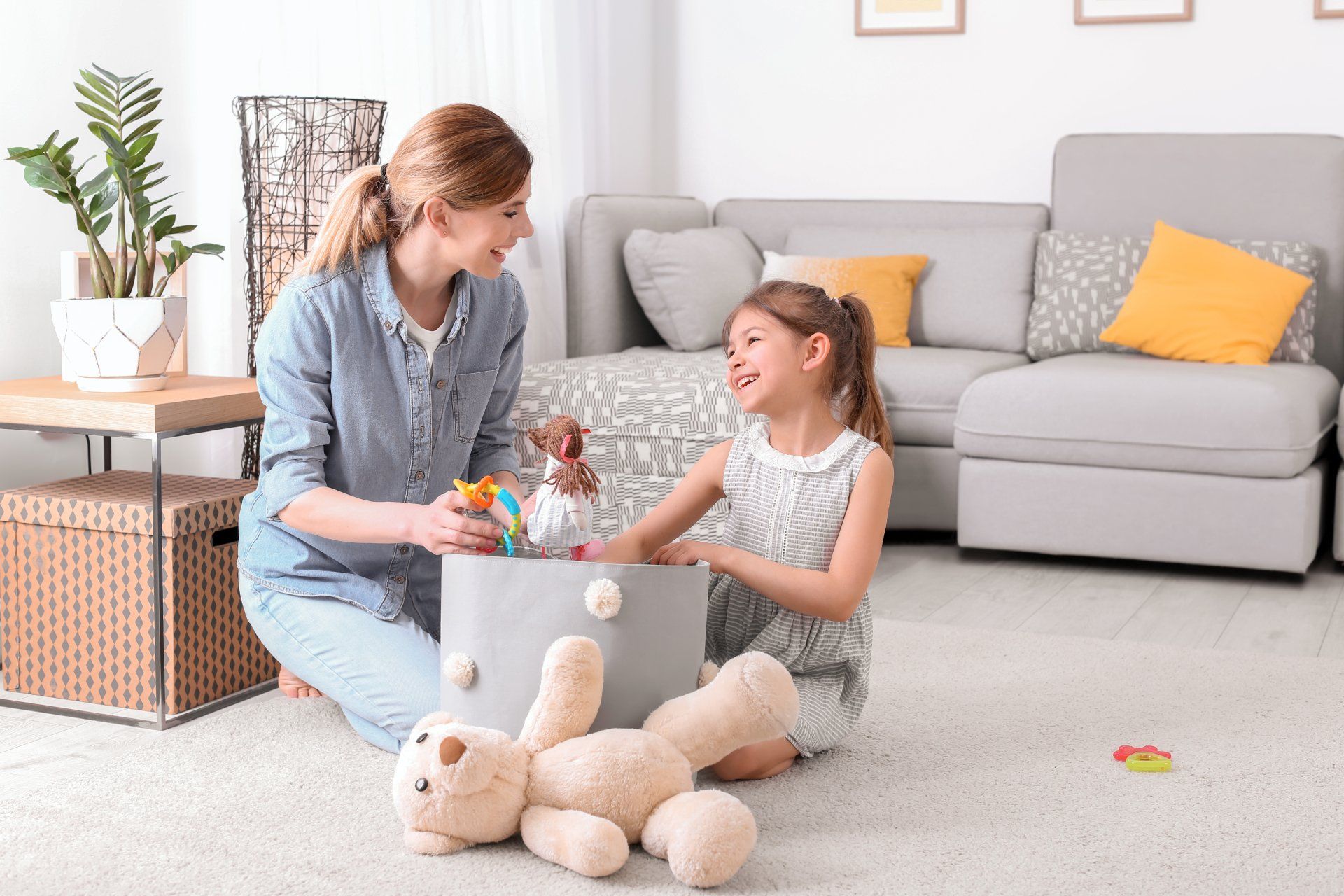 Housewife and daughter picking up toys after playing at home