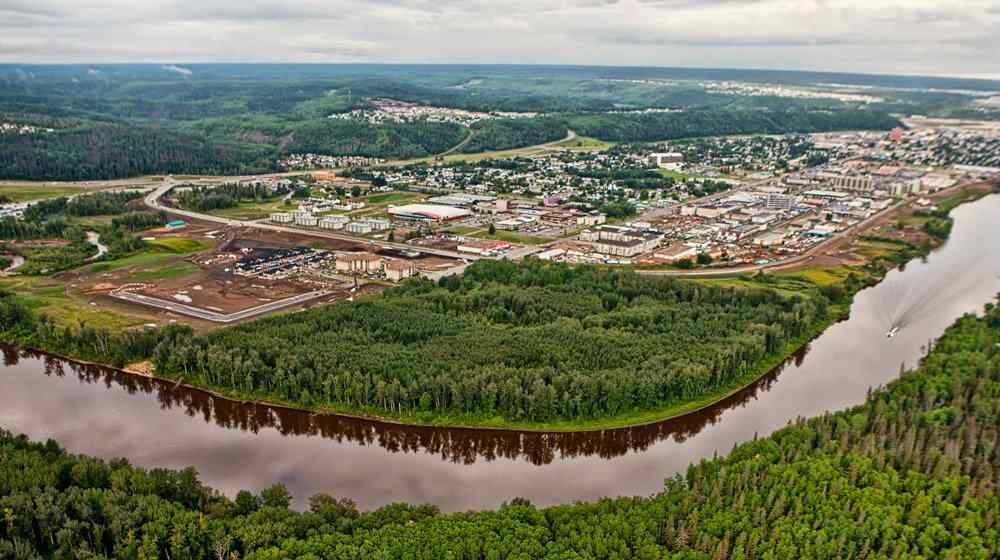 An aerial view of a river surrounded by trees and a city.
