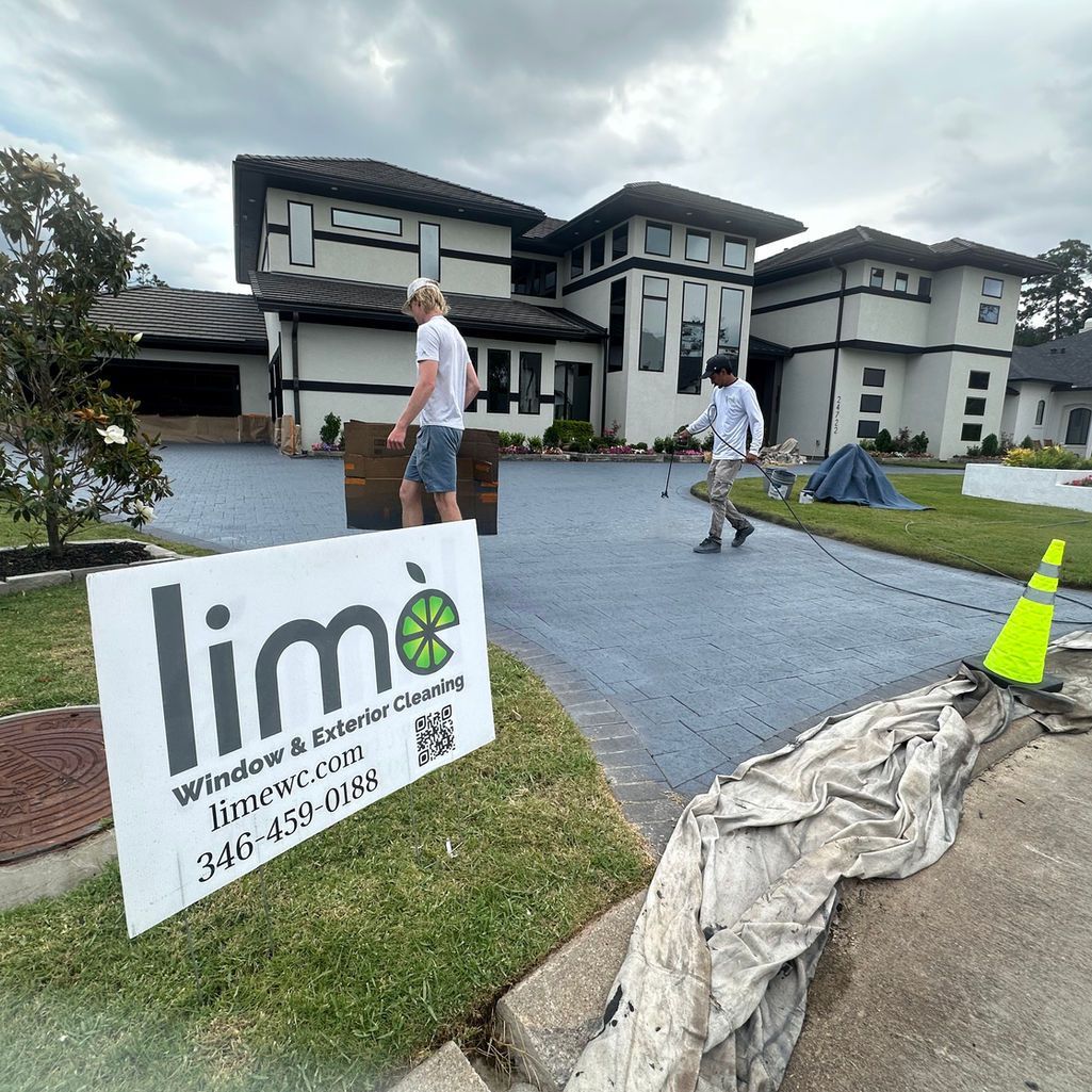 Two workers prepare a driveway at a large white house, with a Lime Painting sign in the foreground.