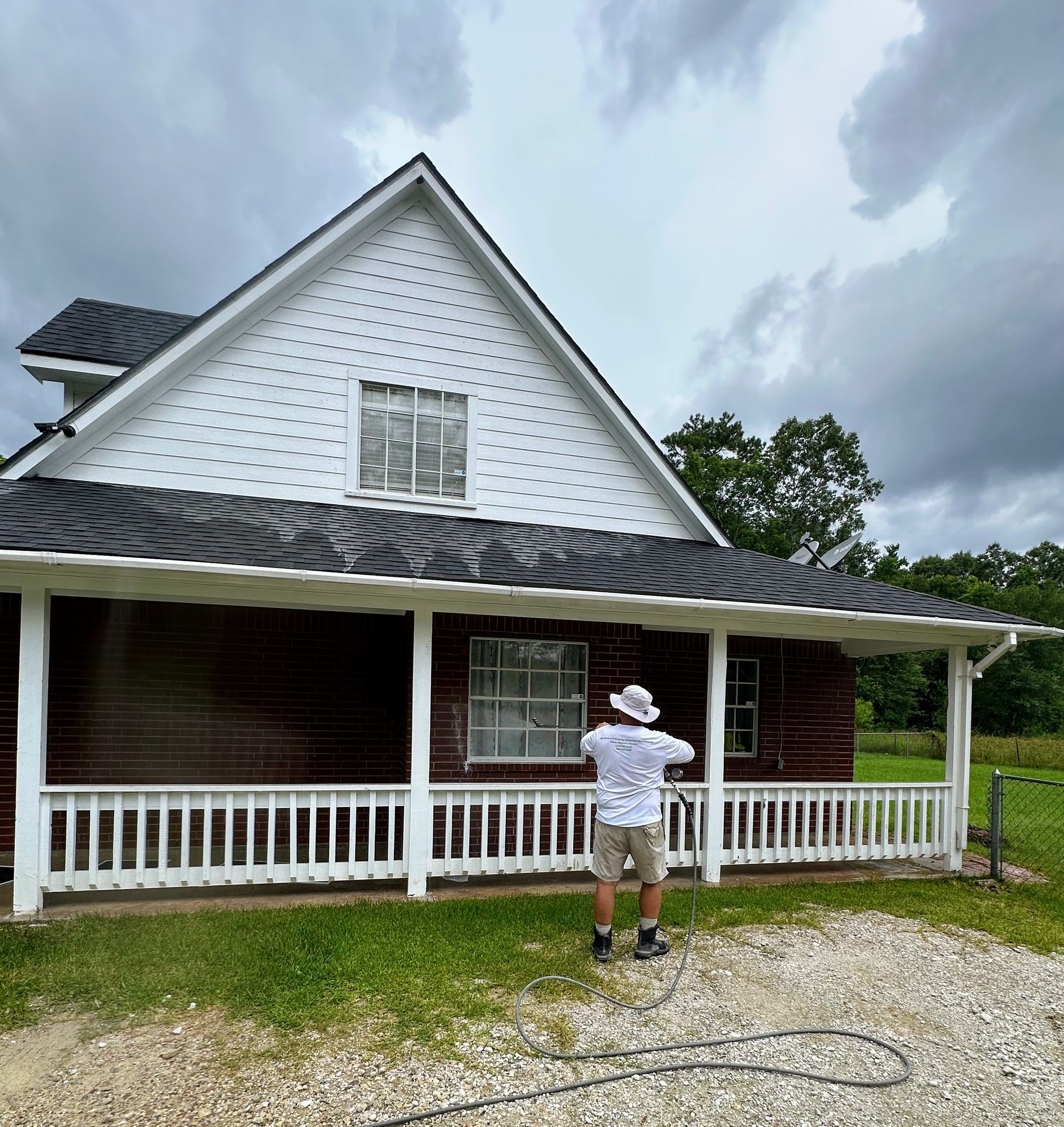 Person painting a white house with a porch under a cloudy sky