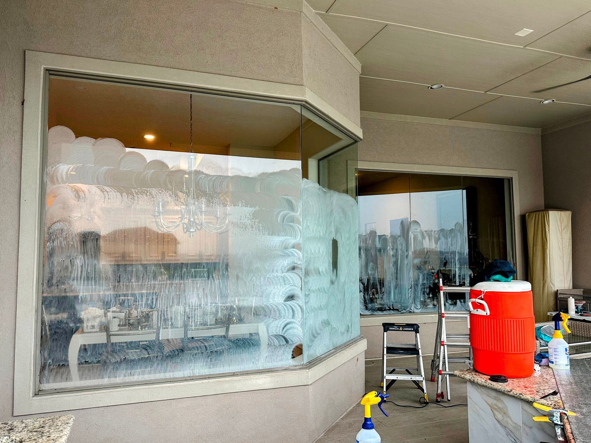 Storefront with frosted windows, a ladder, and a red trash bin outside during construction.