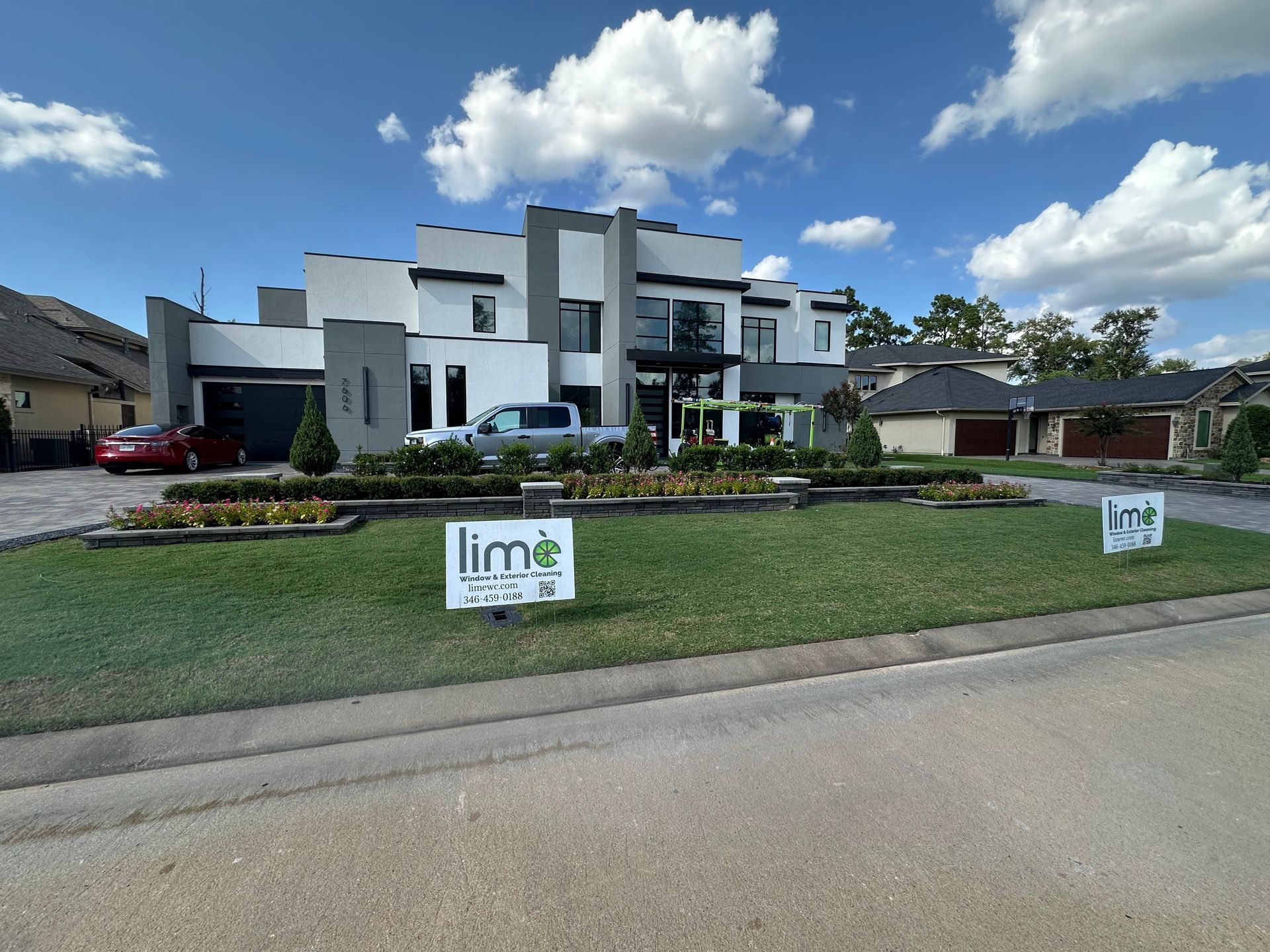 Modern white house under construction with lawn signs along a suburban street under a blue sky