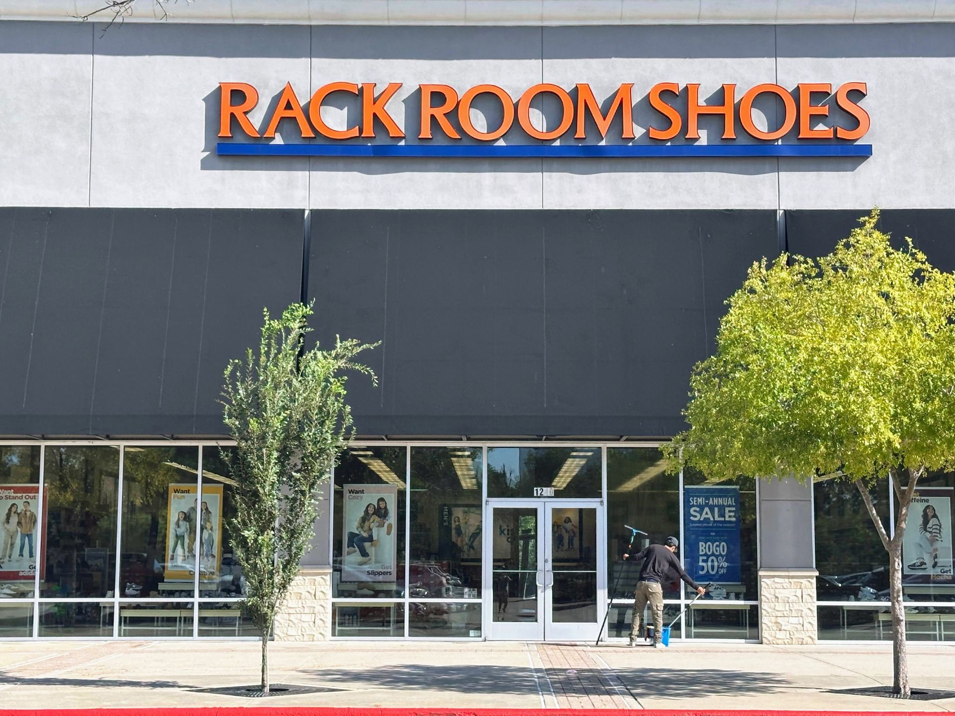 Rack Room Shoes storefront with orange sign and glass entrance on a sunny street