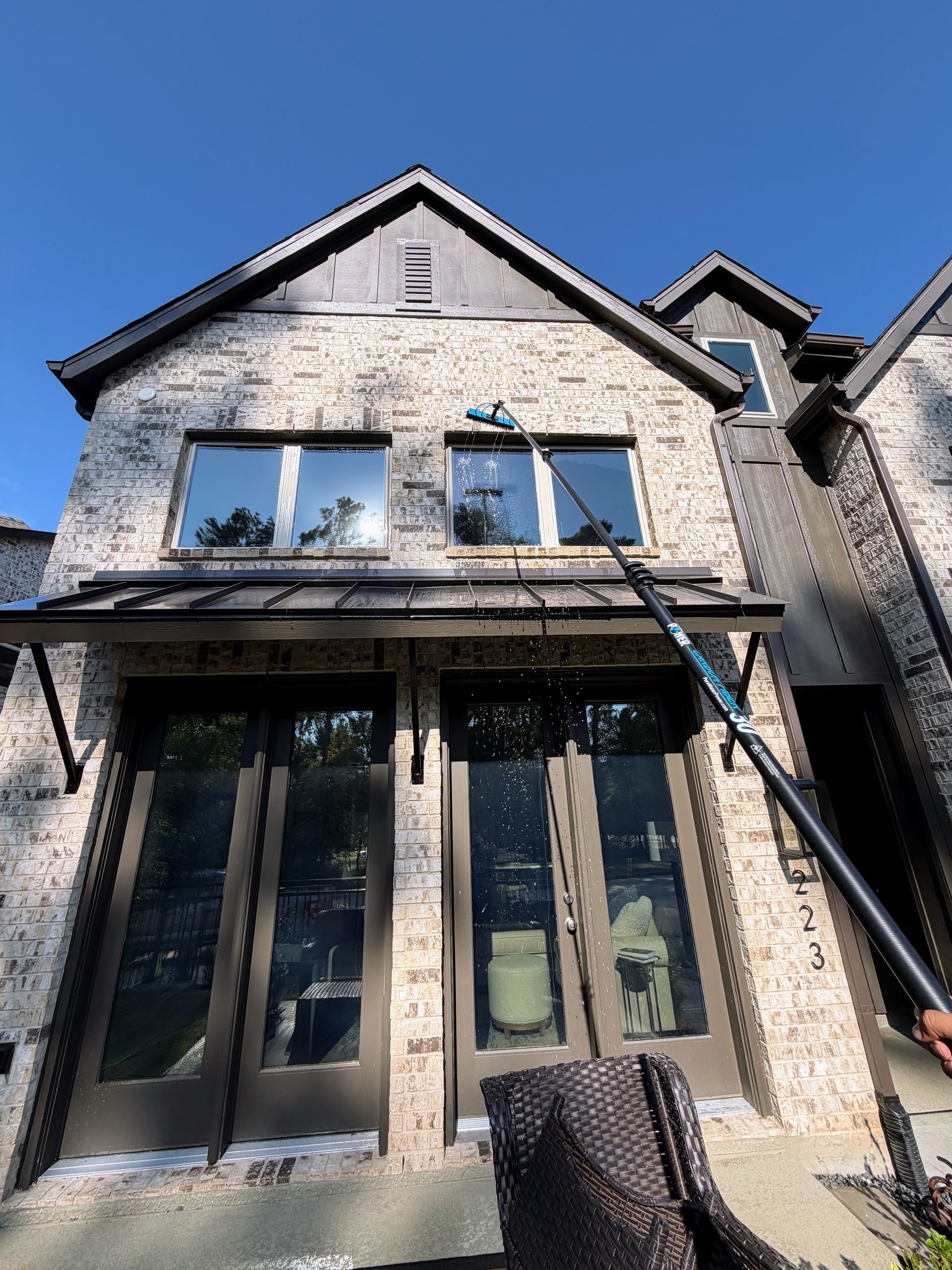 Two-story brick house exterior with black trim and a covered front porch under a blue sky