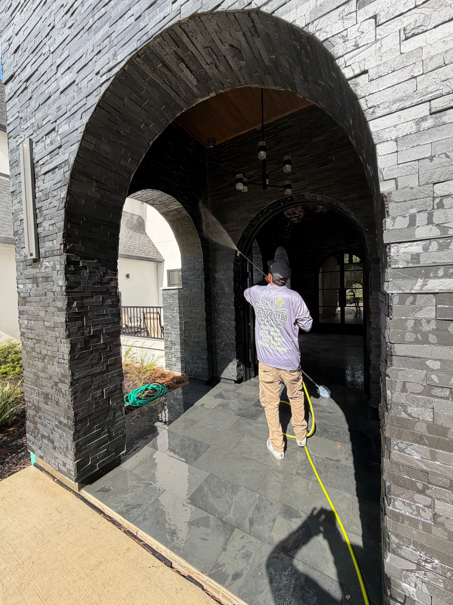 Person walking through a dark stone archway in a sunny courtyard, with a yellow rope on the ground.