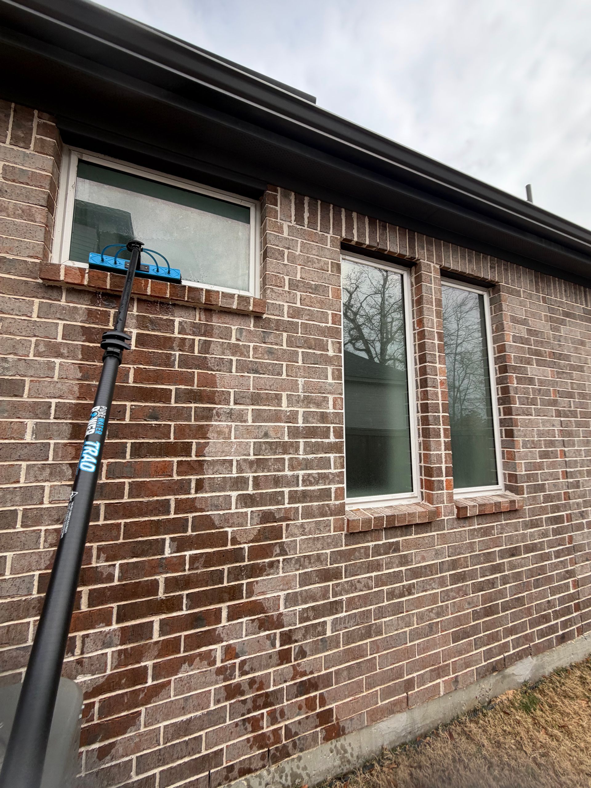 Brick house exterior with a blue utility pole leaning against a window.