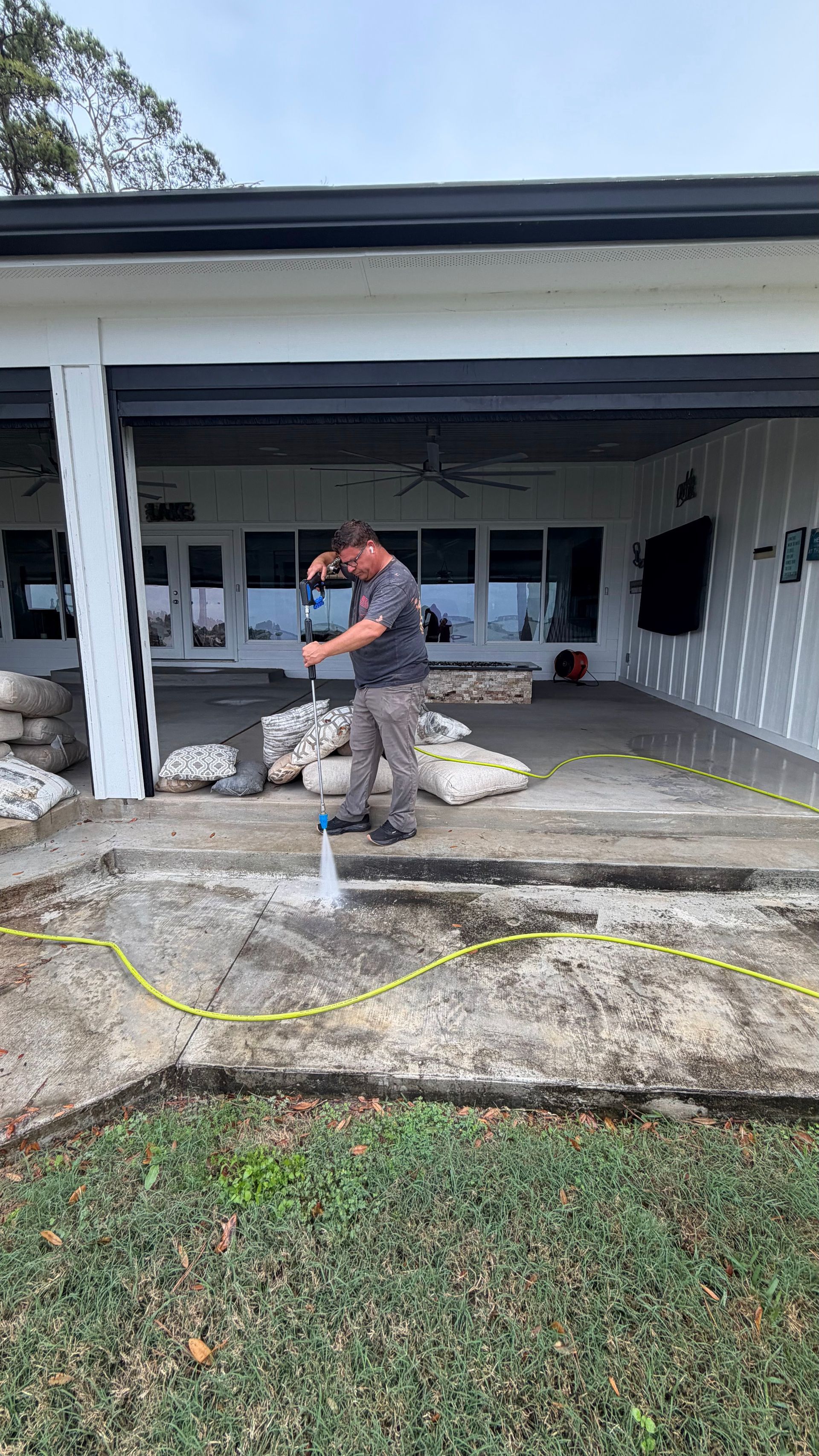 Worker spraying concrete on a covered front porch during home repair work