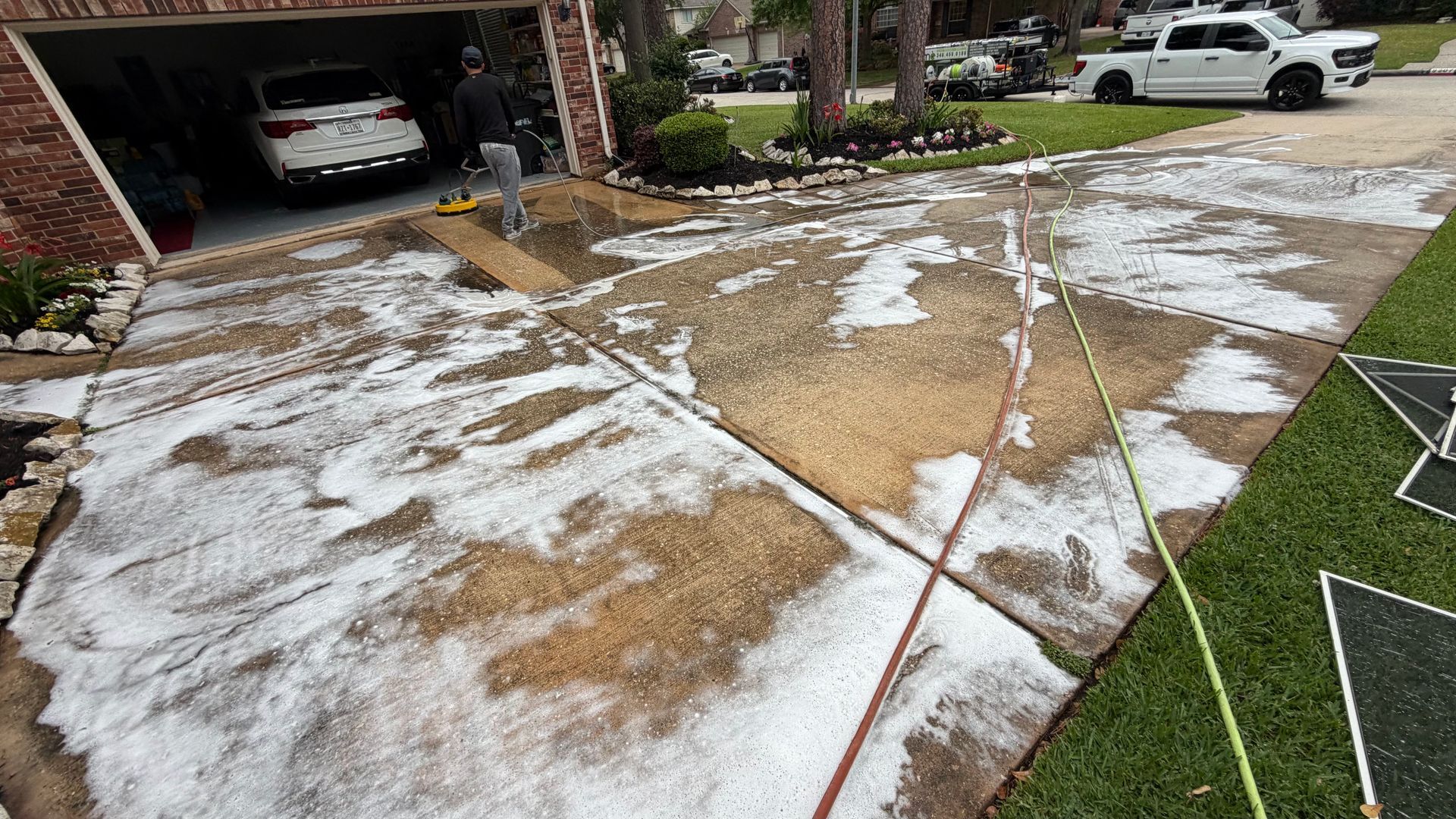 Front yard and driveway covered with patchy snow; hose and debris near an open garage.