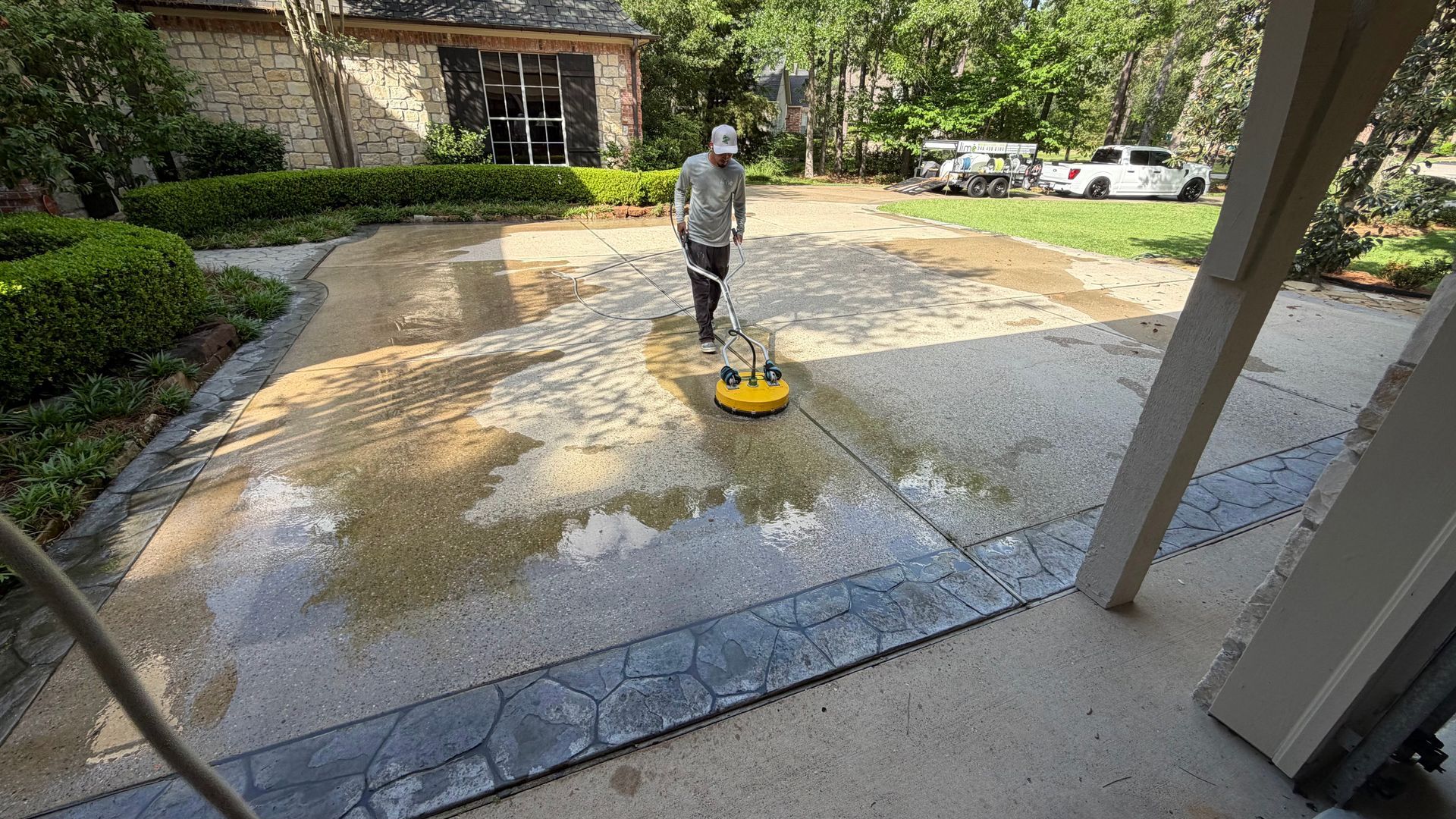 Person pressure-washing a wet driveway in a suburban courtyard