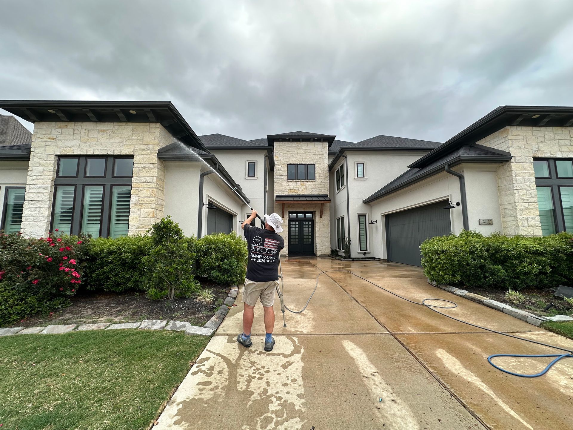 Person standing in a wet driveway between modern houses on an overcast day