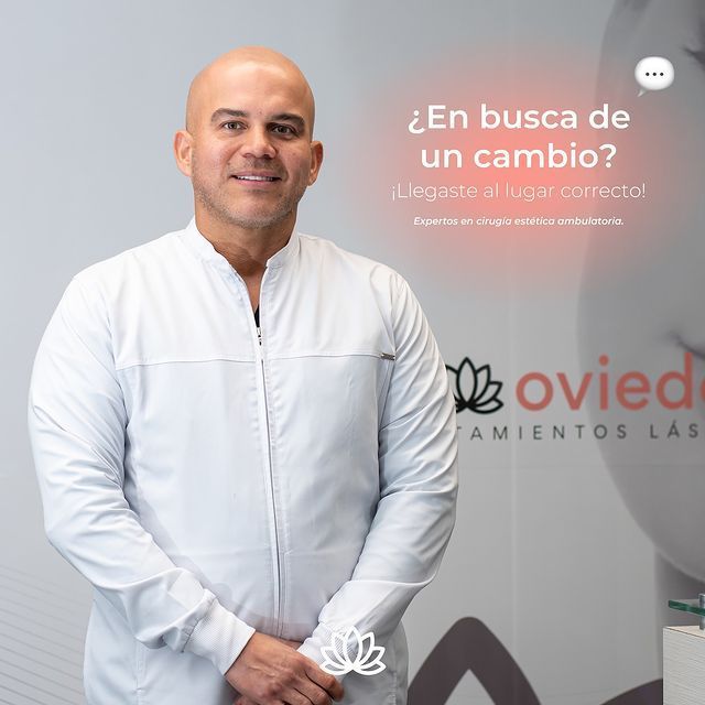 Un hombre calvo con una camisa blanca está parado frente a un cartel que dice
