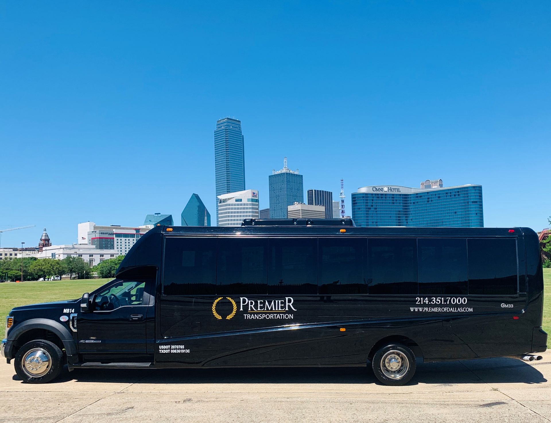 A black shuttle bus is parked in front of a city skyline