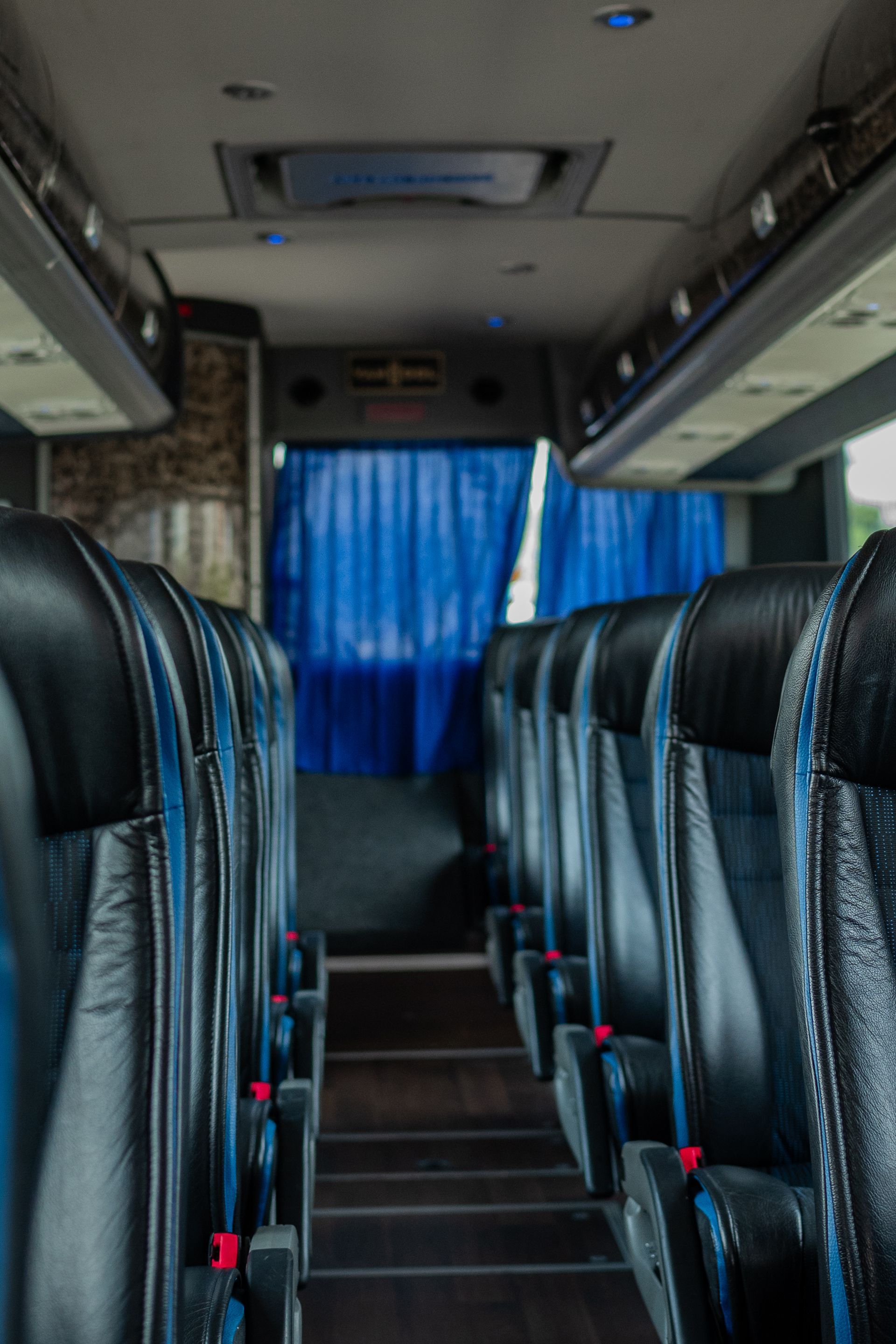 The inside of a bus with blue curtains and black seats