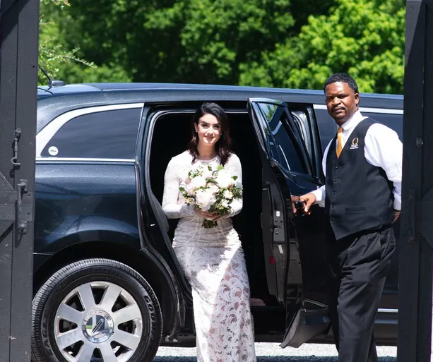 A bride and groom are getting out of a limousine.