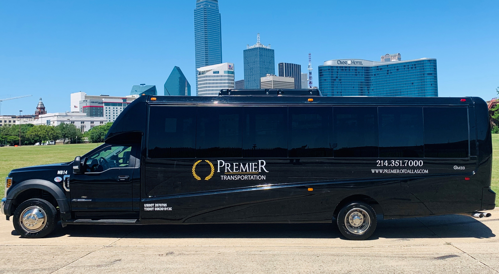 A black shuttle bus is parked in front of a city skyline.