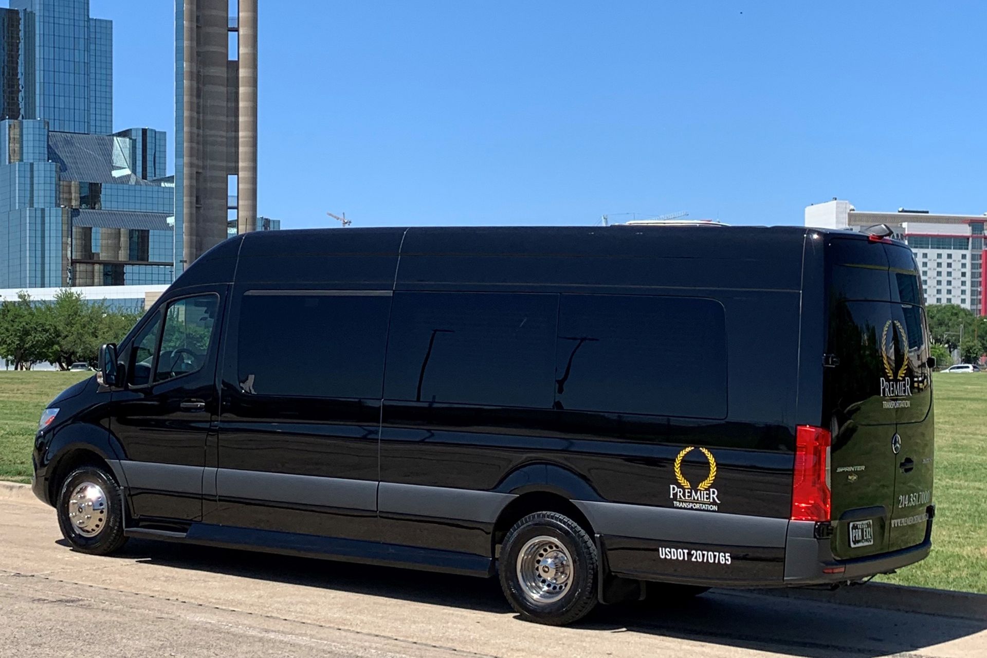 A black van is parked on the side of the road in front of a tall building.