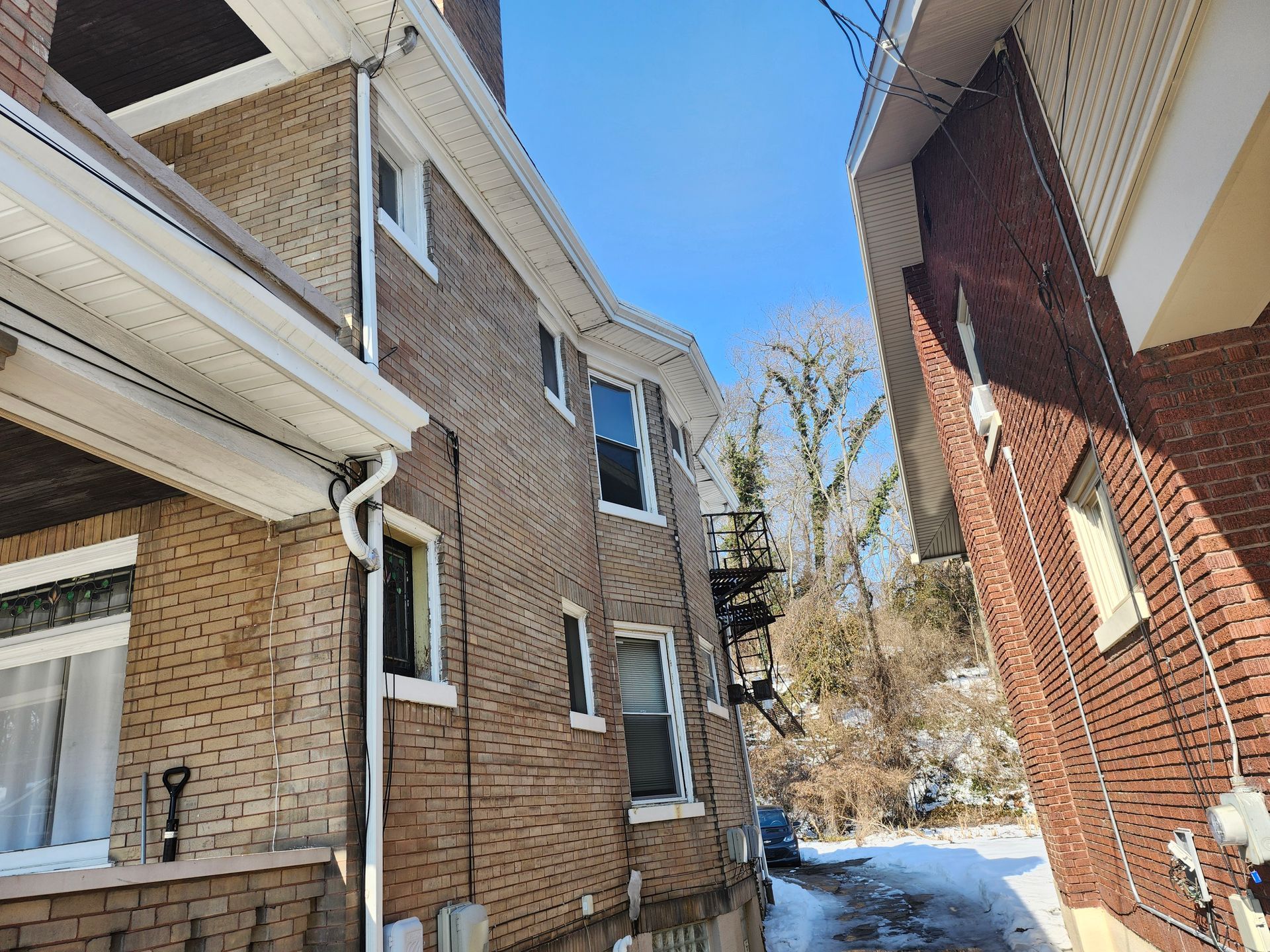 Snowy alley between brick houses under a blue sky