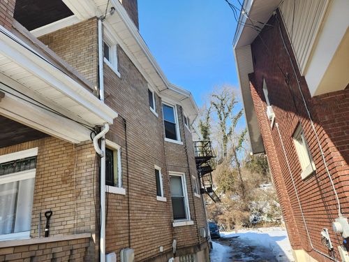 Snowy alley between brick apartment buildings under a bright blue sky