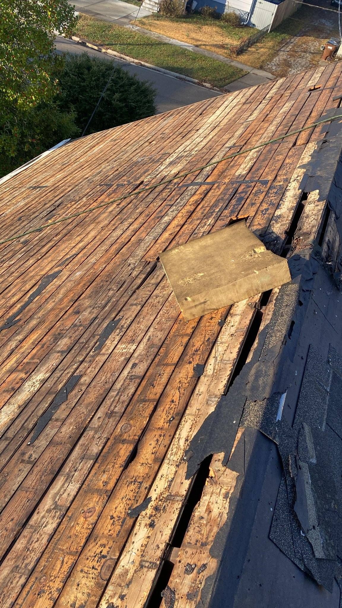 Damaged wooden roof deck with a missing section and exposed gap near the edge