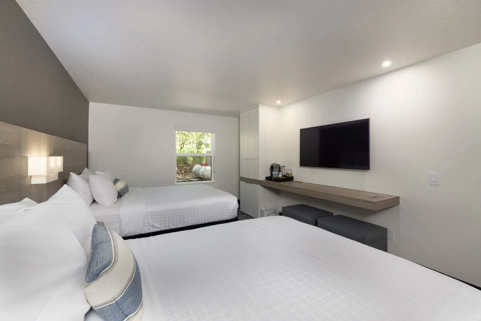 A hotel room with two beds and a flat screen tv.