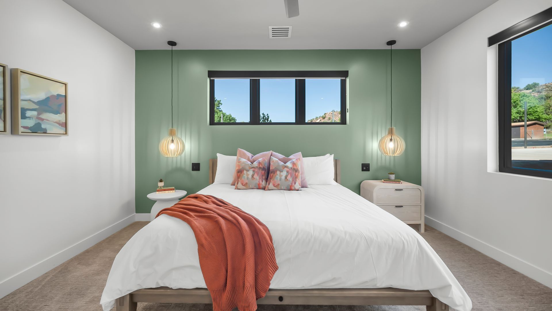 Bedroom with sage green accent wall, bed, and decorative hanging lights.