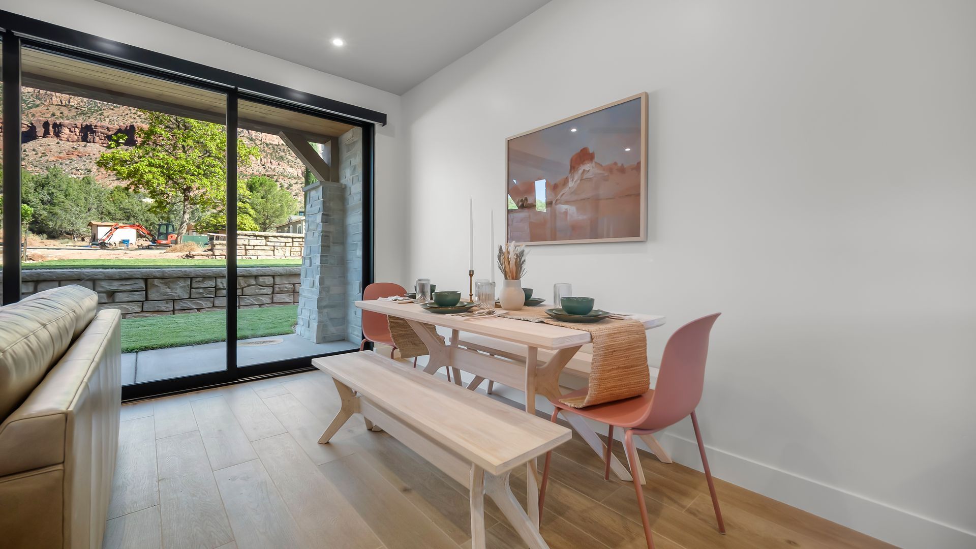 Dining room with table, bench, pink chairs, art, and large window view of red rock landscape.