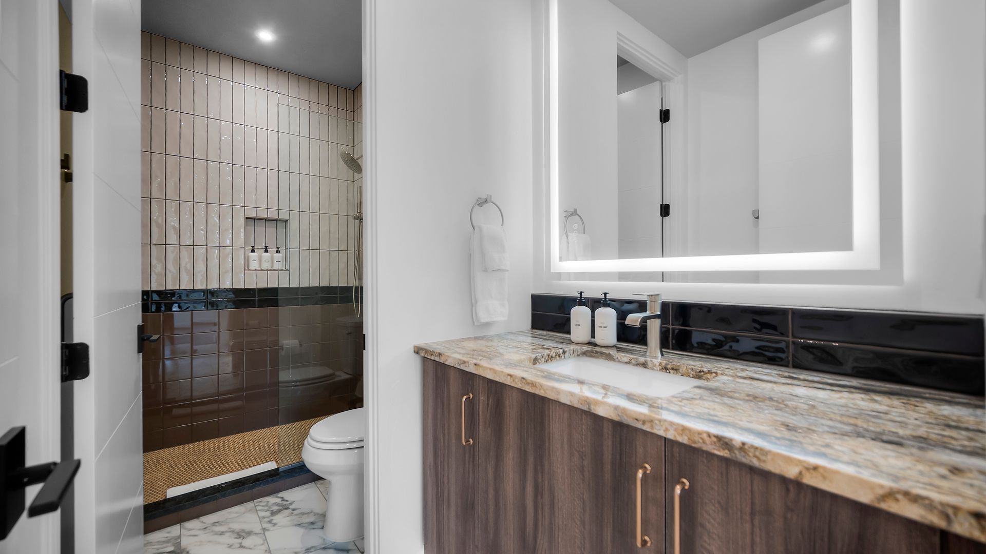 Modern bathroom with a wood vanity, marble countertop, and a walk-in shower.
