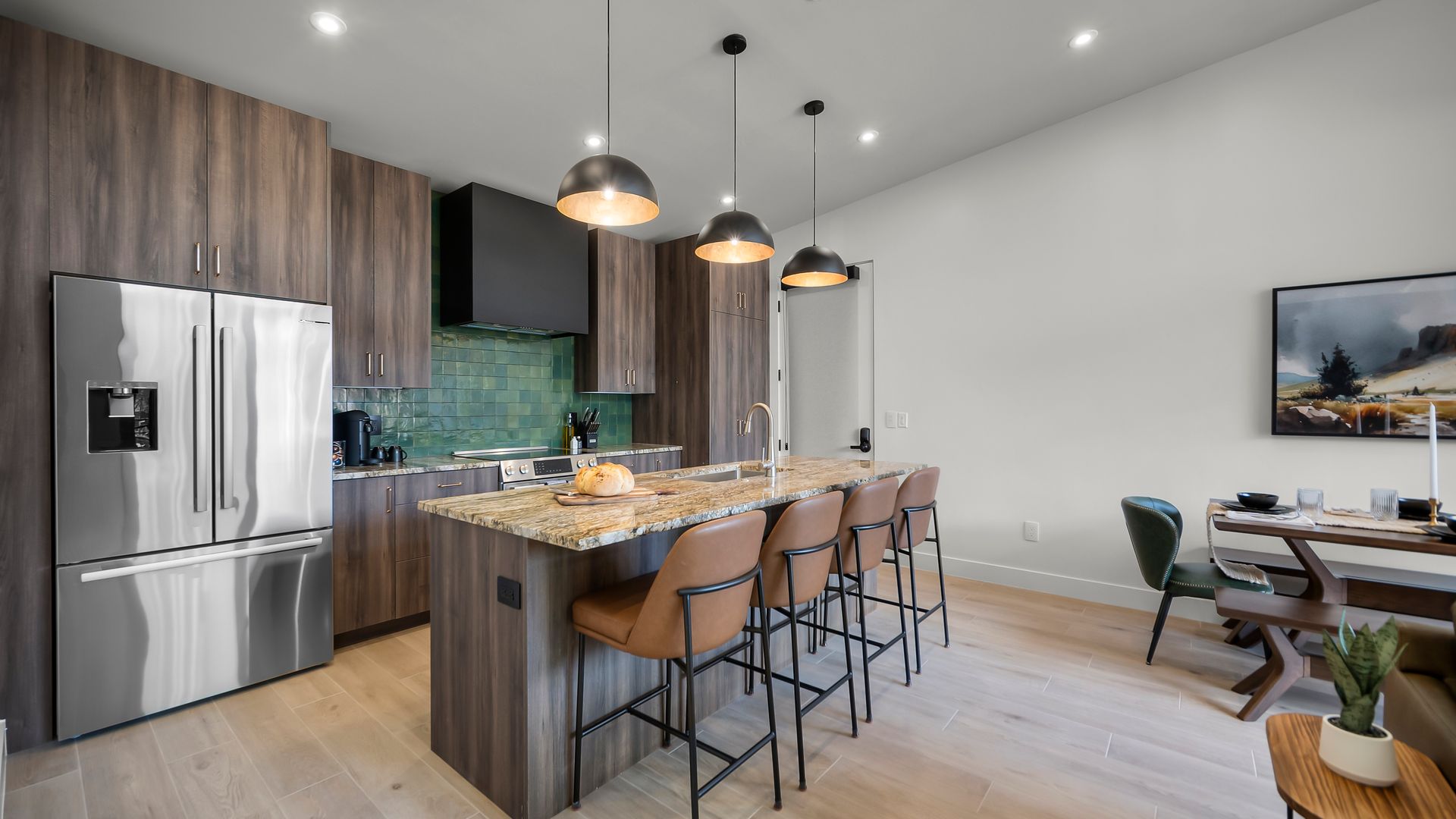 Modern kitchen with wood cabinets, island with stools, stainless steel appliances, and pendant lights.